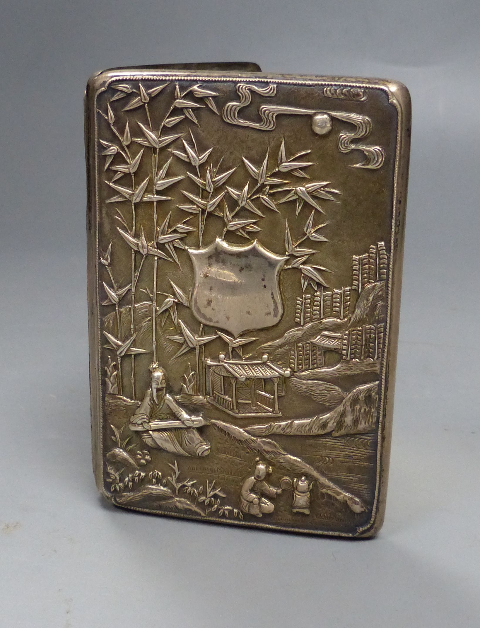 A late 19th century Chinese Export white metal card case, decorate with figures at various pursuits in landscape scene,